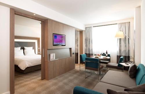 a hotel room with a bed and a living room at Novotel Sofia in Sofia