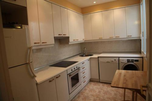 La cuisine est équipée de placards blancs et d'un réfrigérateur blanc. dans l'établissement Apartamento Journalist, à Saint-Sébastien