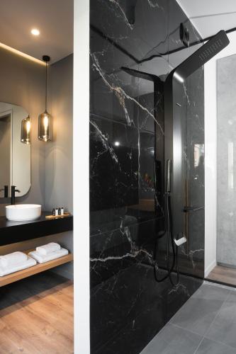 a bathroom with a shower with black marble walls at LUX&EASY Athens Downtown Apartments in Athens