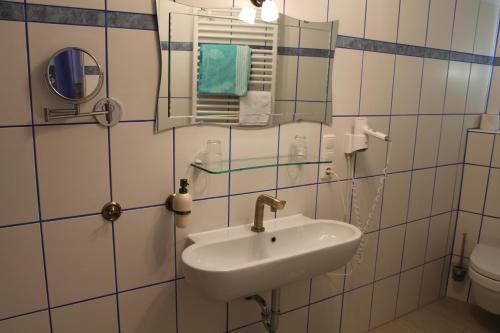 uma casa de banho com um lavatório, um espelho e um WC. em Kreuzerhof Hotel Garni em Rothenburg ob der Tauber