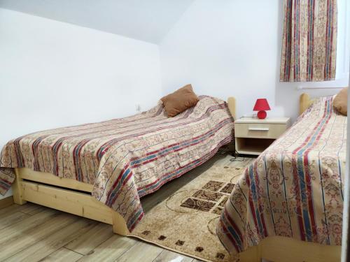 a bedroom with two beds and a table with a lamp at Cabana 84 in Beclean