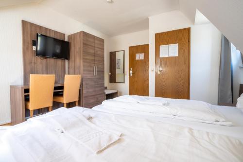 a bedroom with a bed and a desk and a television at Mühlengarten by Relax Inn - Staffless & Self Check-In in Nittel