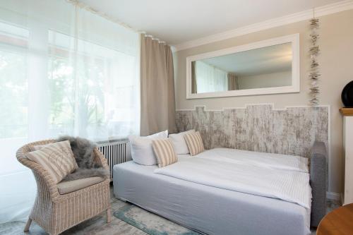 - une chambre avec un lit, une chaise et un miroir dans l'établissement Ferienwohnung StrandKoje-OstseeBlick im Strandschloss, à Grömitz