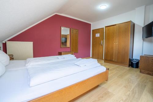 a bedroom with a large bed with a red wall at Mühlengarten by Relax Inn - Staffless & Self Check-In in Nittel