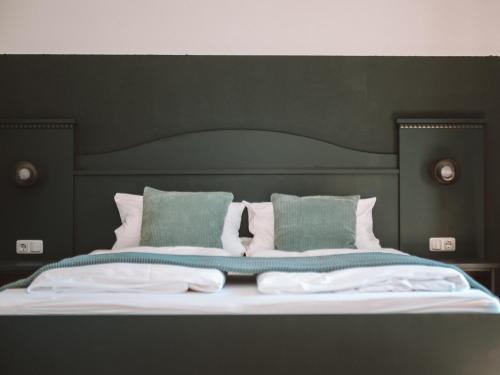 a bed with a black headboard and green pillows at LEDA AM ECK in Bad Wiessee
