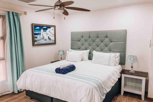 a bedroom with a large white bed with a fan at Pecanwood Golf Estate Home - Hartbeespoort in Hartbeespoort