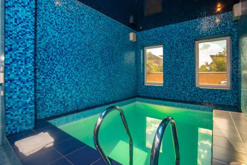 een blauwe betegelde badkamer met een bad en 2 ramen bij Отель Корона in Dnipro