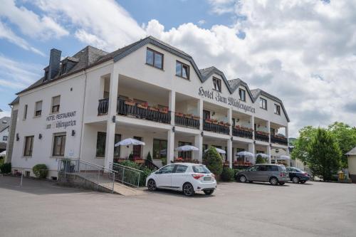 a large white building with cars parked in a parking lot at Mühlengarten by Relax Inn - Staffless & Self Check-In in Nittel