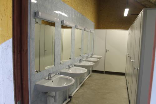 ein Bad mit einer Reihe von Waschbecken und Spiegeln in der Unterkunft Pūķarags - Kempings in Pape
