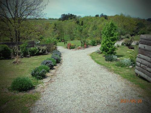 a gravel path in a garden with bushes and trees at Gîte de Rouviac in Castelnau-Pégayrols