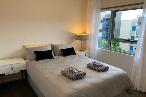 a bedroom with a bed with two towels on it at Sunny Balcony Over a Calm Private Garden in Melbourne
