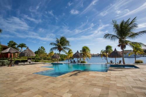 威廉斯塔德的住宿－Spanish Water View Apartment，棕榈树和水体的度假游泳池