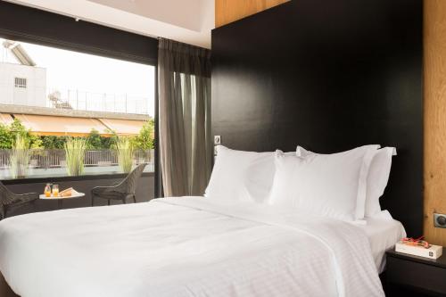 a bedroom with a white bed and a large window at LUX&EASY Athens Downtown Apartments in Athens