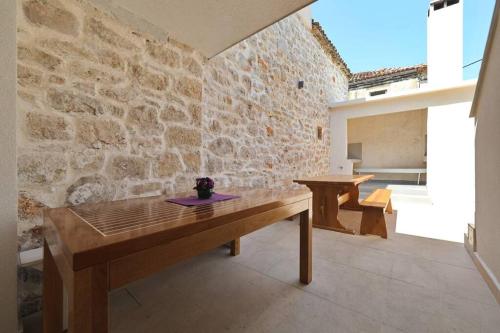 a wooden table in a room with a stone wall at Stone house in the center of Murter town in Murter