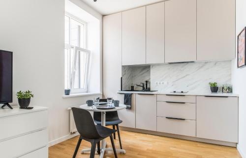 a kitchen with white cabinets and a table and chairs at Cozy Modern Studio in City Centre & QueenSize Bed in Rīga