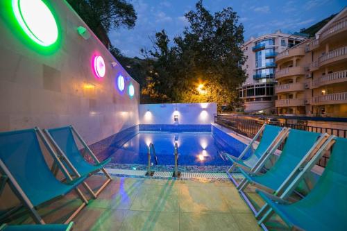 a swimming pool with two blue chairs and a building at Villa Katarina in Budva