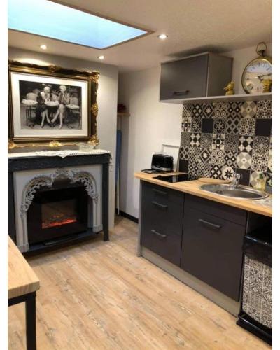 - une cuisine avec une cheminée, un évier et une cuisinière dans l'établissement Appartement romantique parisien, baignoire rétro au pied du lit, à Boulogne-sur-Mer