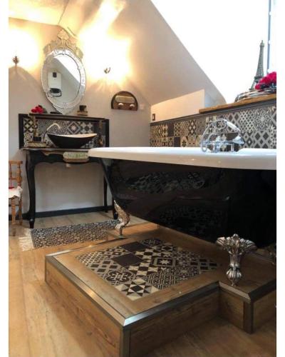une salle de bain avec une baignoire, un lavabo et un miroir dans l'établissement Appartement romantique parisien, baignoire rétro au pied du lit, à Boulogne-sur-Mer