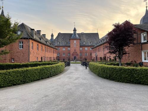 a courtyard of a large brick building with bushes at Ferienwohnungen Jagdschloss Adolphsburg in Kirchhundem