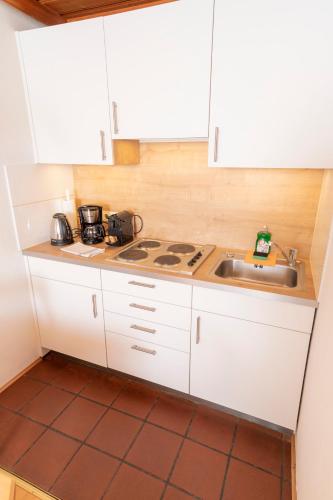 a kitchen with white cabinets and a sink at Appartements Bernhofer in Saalbach Hinterglemm