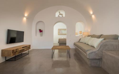 a living room with a couch and a tv at AQUA SERENITY LUXURY SUITES SANTORINI in Foinikiá