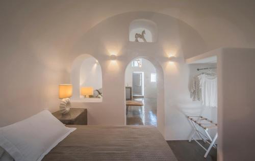 una camera con letto e una camera con sedia di AQUA SERENITY LUXURY SUITES SANTORINI a Foinikiá