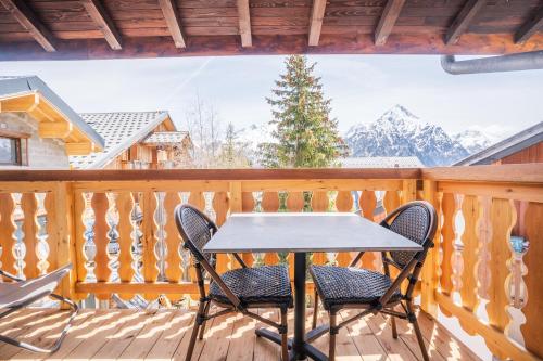a table and chairs on a deck with snow covered mountains at cellier 6 in Les Deux Alpes