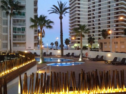 einen Pool in einer Stadt mit Palmen und Gebäuden in der Unterkunft Hotel Santamarta in Cullera