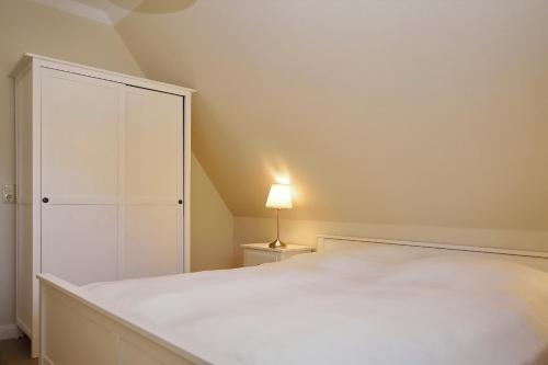 a bedroom with a white bed and a lamp at An der Steilküste Wohnung 03 in Boltenhagen