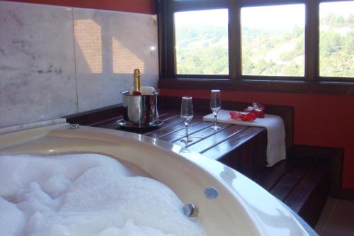 a bath tub in a room with a table and windows at Pousada Recanto dos Sonhos in Campos do Jordão