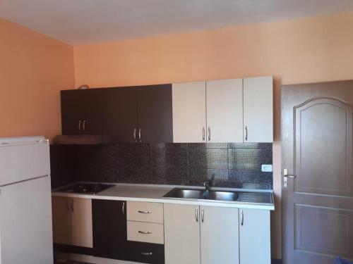 een keuken met witte kasten, een wastafel en een koelkast bij Apartament in Shëngjin
