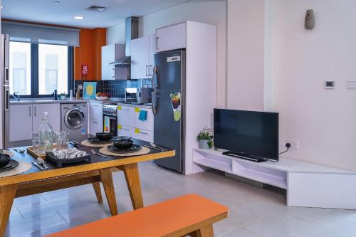 a kitchen with a refrigerator and a table with a tv at Lovely Ensuite Rooms for STUDENTS ONLY , DUBAI - SK in Dubai
