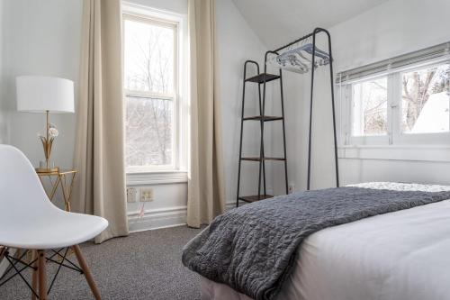 a bedroom with a bed and a chair next to a window at The Blue House on Front Downtown Traverse City in Traverse City