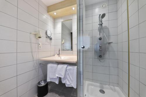 a white bathroom with a shower and a sink at Hôtel Restaurant et Spa Au Tilleul in Labaroche