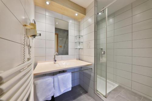 a white bathroom with a sink and a shower at Hôtel Restaurant et Spa Au Tilleul in Labaroche