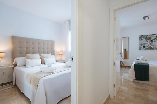 um quarto com uma grande cama branca e uma casa de banho em Triana Home - Free Parking em Sevilha