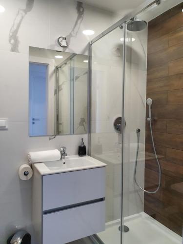a white bathroom with a sink and a shower at Kolory Lata - 365PAM KLIMATYZACJA I PLAC ZABAW W OBIEKCIE in Sarbinowo