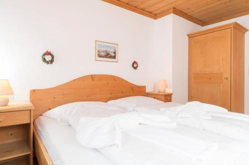 a white bed in a bedroom with two night stands at Appartements Bernhofer in Saalbach Hinterglemm