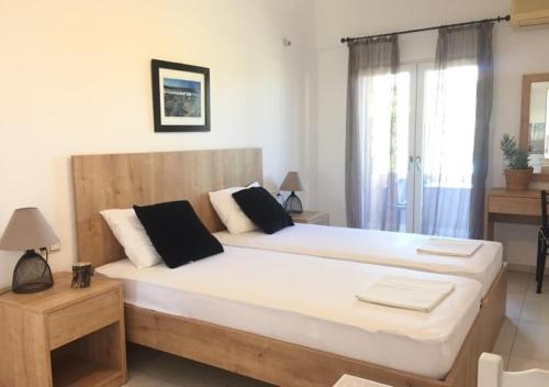 a bedroom with a large white bed with black pillows at Minoica Beach Apartments in Amoudara Herakliou