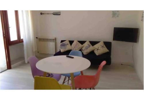 a living room with a table and chairs and a couch at Bilocale a pochi metri dal mare in La Maddalena
