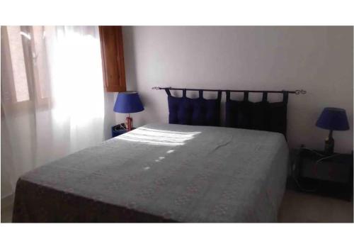 a bedroom with a bed and two lamps and a window at Bilocale a pochi metri dal mare in La Maddalena