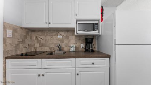 a kitchen with white cabinets and a sink and a microwave at Beau Rivage Beach Resort in Wildwood Crest
