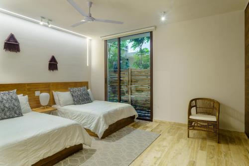 a bedroom with two beds and a chair and a window at Private pool apartment for groups in Tulum