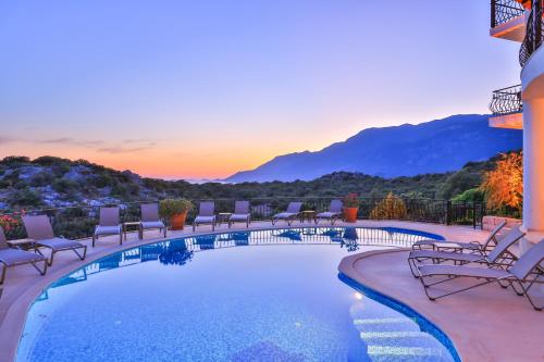 a swimming pool with chairs and a sunset in the background at Hill House Adult Only in Kas