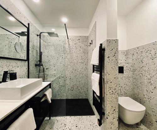 a white bathroom with a sink and a toilet at Hôtel 16 | 150 Montagne & Spa Nuxe in Vars
