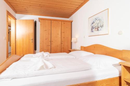 two white beds in a bedroom with wooden ceilings at Appartements Bernhofer in Saalbach Hinterglemm