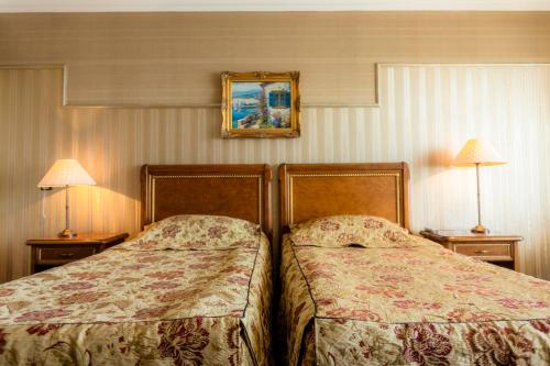 two beds in a hotel room with two lamps at Hotel Palace Marina Dinevi in Sveti Vlas