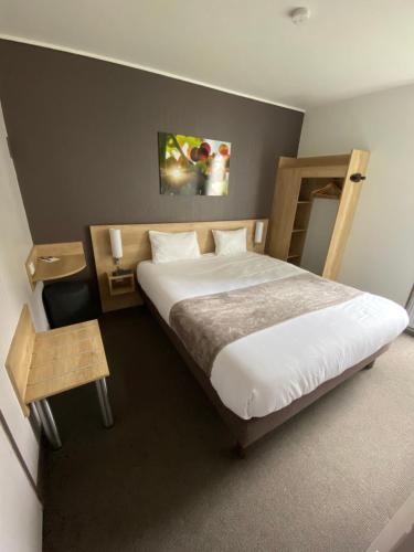 a bedroom with a large bed with white sheets at Hotel Wood Inn Bordeaux Aéroport in Mérignac