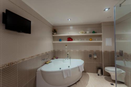 a bathroom with a tub and a toilet and a television at Hotel Palace Marina Dinevi in Sveti Vlas