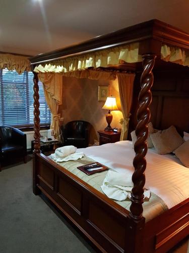 a large canopy bed in a bedroom with a lamp at Wessex Hotel in Street